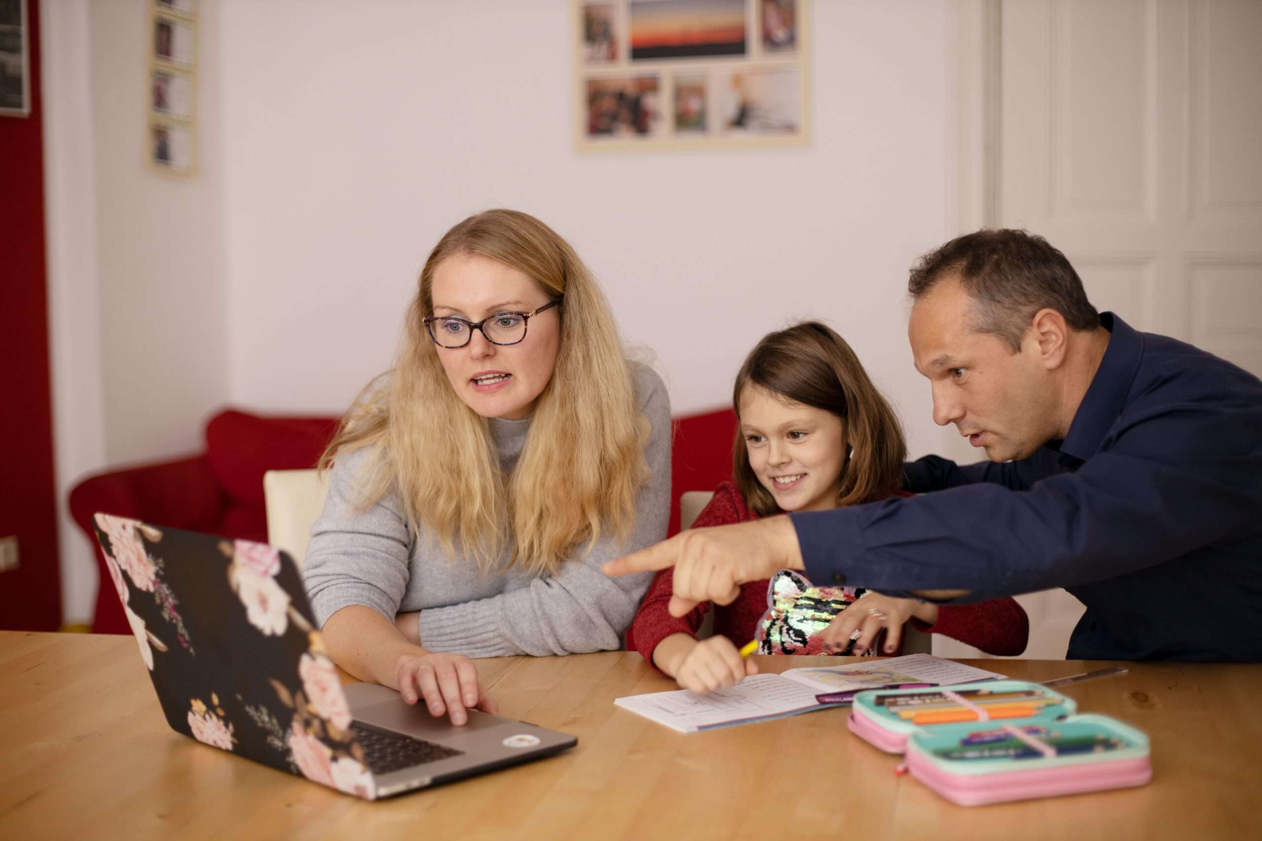 Mutter und Vater die ihrem Kind im Laptop etwas zeigen